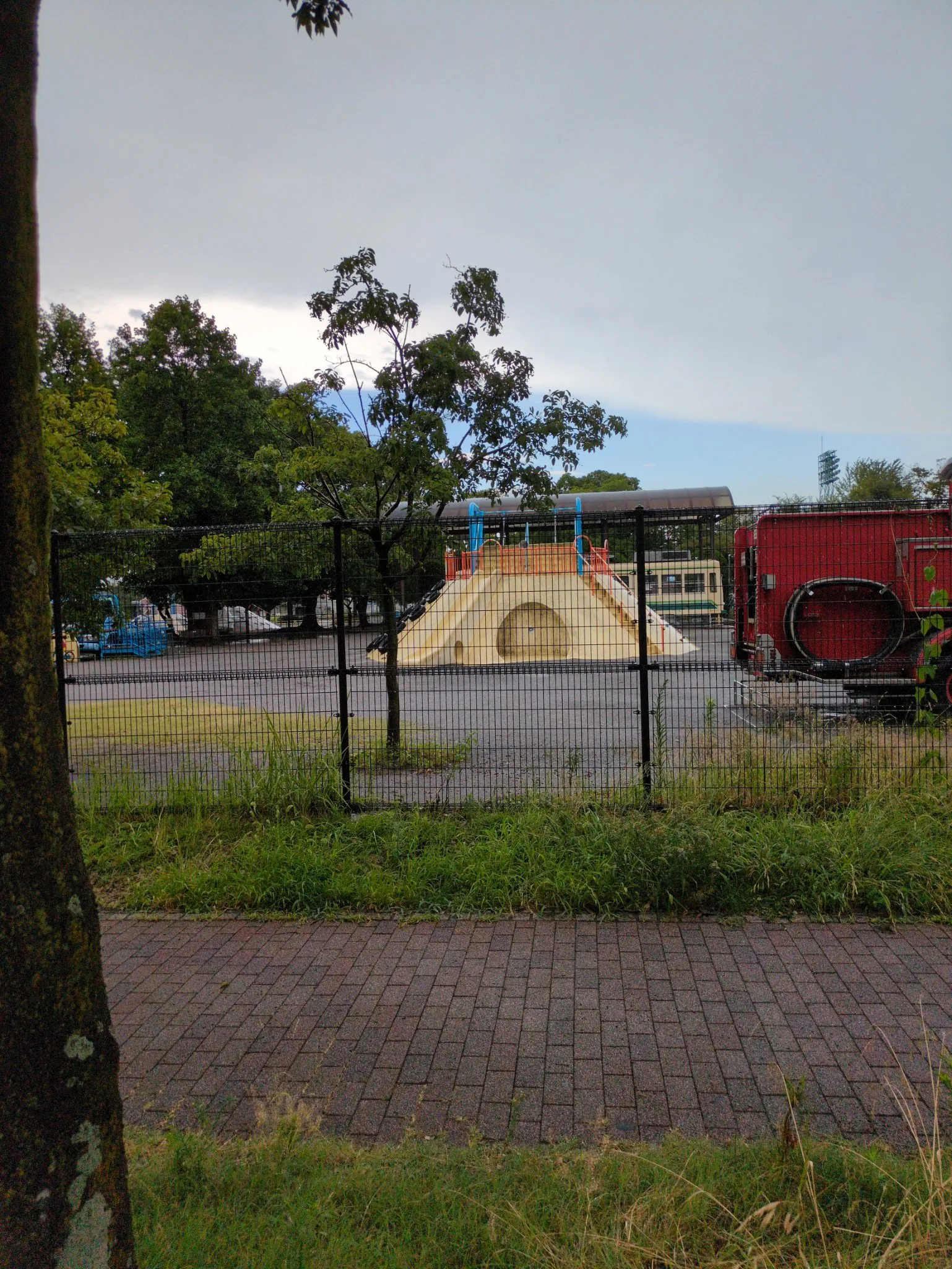 雨上がりの萩中公園。柵の向こうに残る車両と遊具